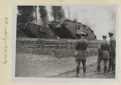 Three officers, one possibly King George V, watching two tanks being driven over an obstacle, 1915-18 by English Photographer